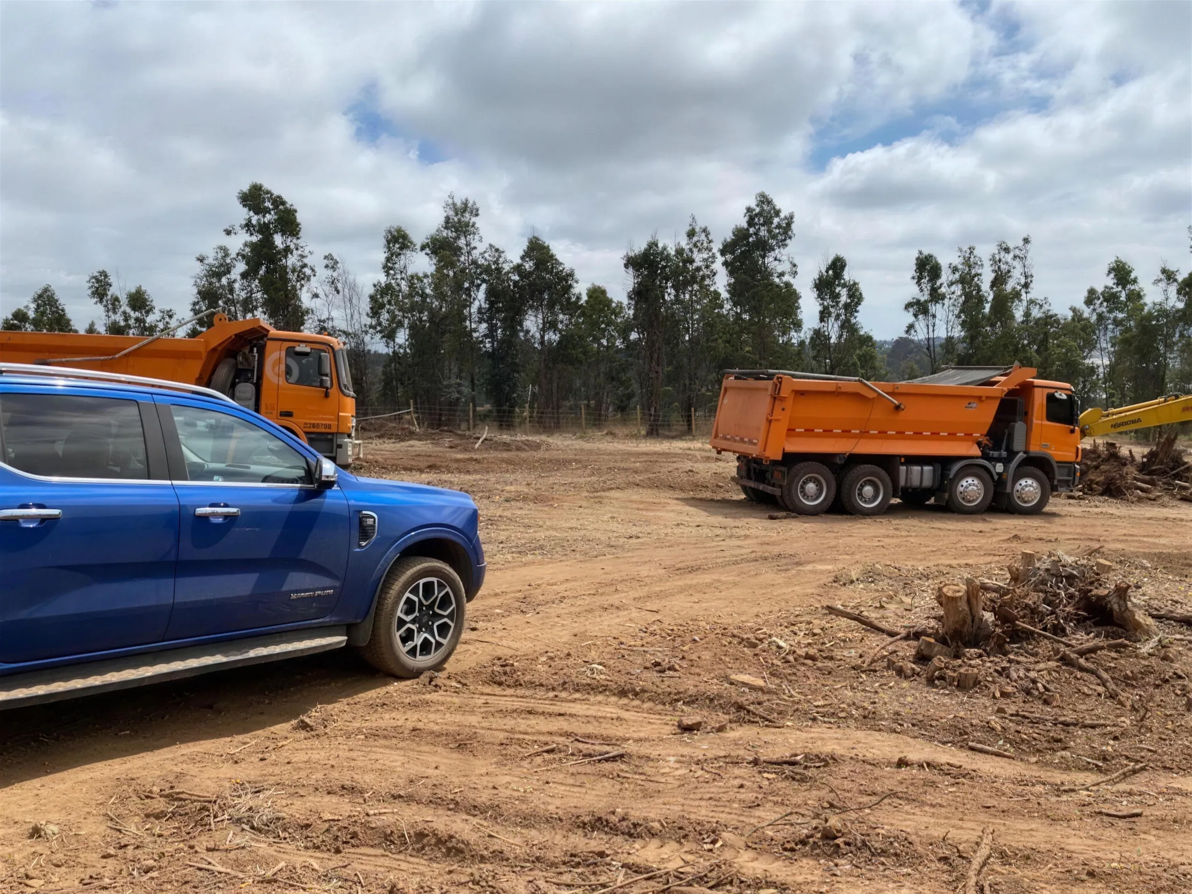 Camioneta y camiones tolva de DEXA Chile en una faena de despeje de terreno